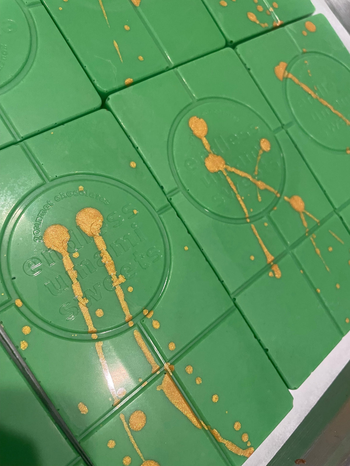 Pandan white chocolate bar with green chocolate and gold splatter by Endless Umami Sweets.